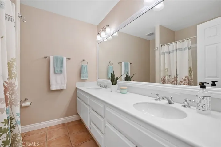 Double vanity shared bathroom featuring a tub/shower and tile flooring.