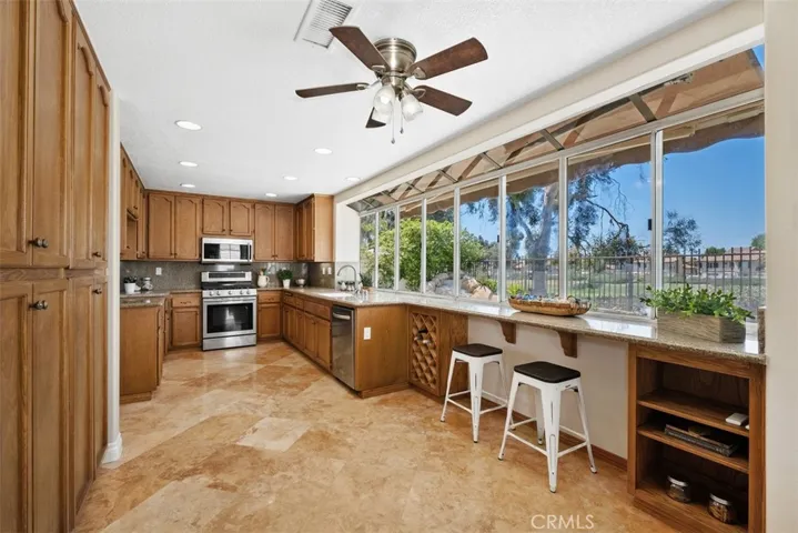Enjoy cooking while taking in views of your outdoor living space. Stainless steel appliances, travertine flooring,  and plenty of cabinetry in this kitchen make everyday tasks a joy!