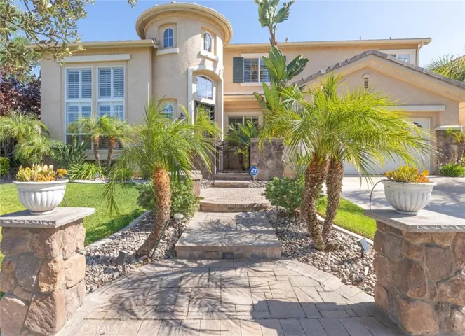 The inviting entryway features a beautifully paved walkway framed by stone pillars, creating a warm and welcoming first impression.