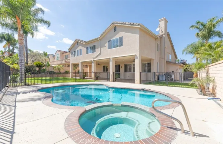 The backyard offers a personal oasis with a sparkling pool and relaxing spa, a large covered patio perfect for family gatherings or quiet evenings.