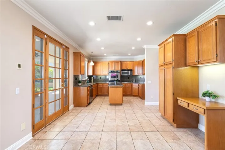 
The kitchen features granite countertops, stainless steel appliances, and French doors that open to the outdoor patio area.