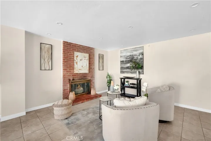 cozy fireplace with brick accents, a raised hearth, and glass doors