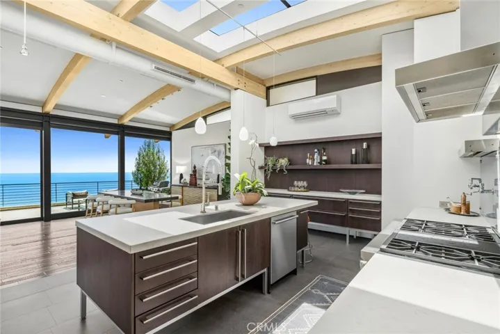 Skylights illuminate the adjacent kitchen, where custom Siematic cabinetry, open shelving and Caesarstone countertops are proudly displayed.
