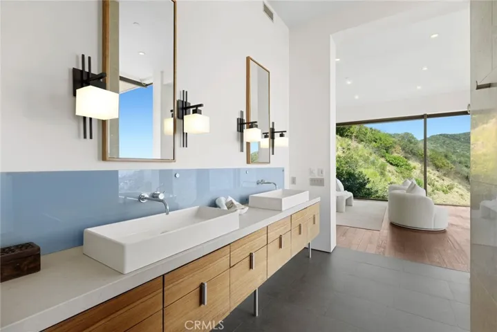 The lux primary bedroom and bath boast an oversized walk-in shower with incredible ocean views, a freestanding soaking tub and a spacious walk-in closet.
