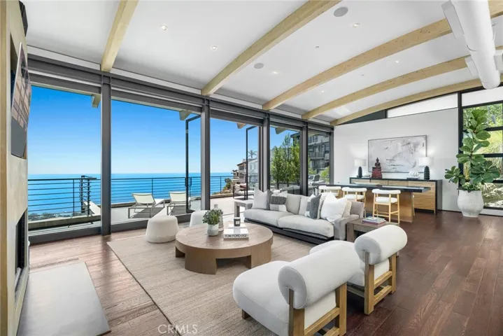 On the main level, windows envelop an impressive great room crowned by an arched and beamed ceiling that soars over the living and dining areas.