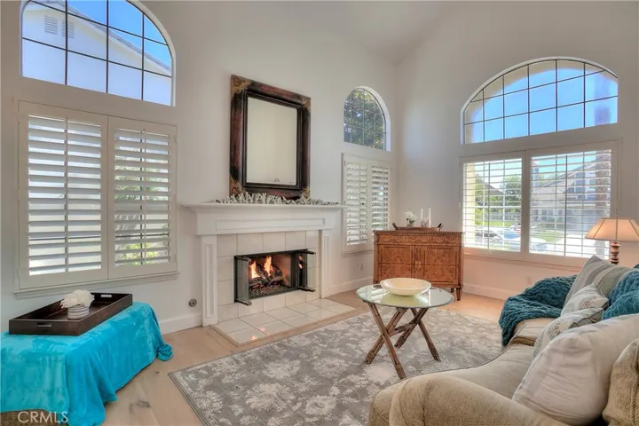 Custom fireplace, wood flooring, and high windows create a light and bright living room experience