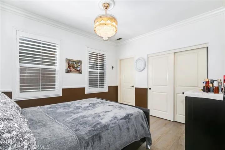 First level bedroom with chandelier, trach closet with built-in organizer