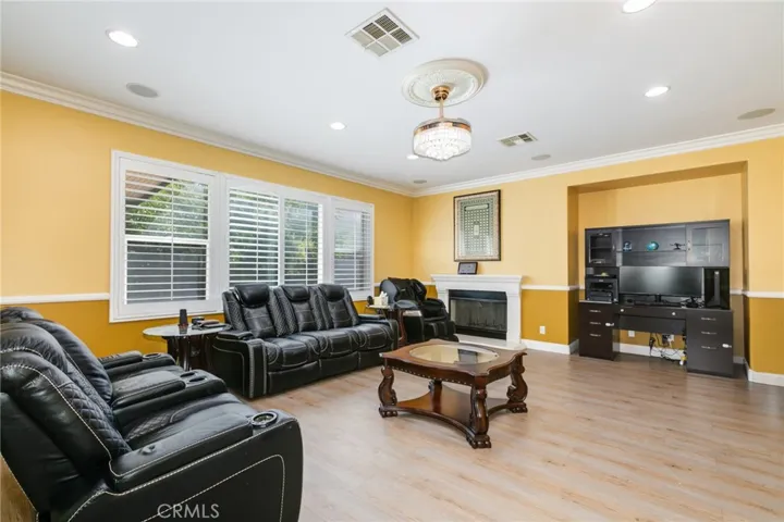 Family room with chandelier/fan and recess lighting. Fireplace with kit and lots of windows for natural light.