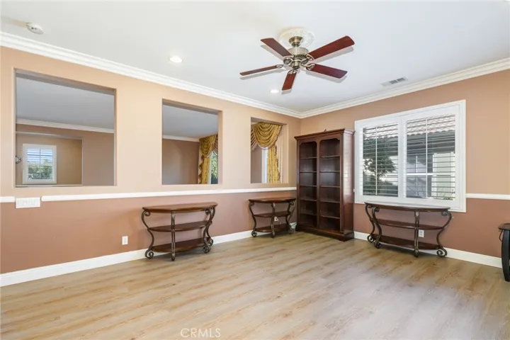Upstairs loft area with ceiling fan, crown molding, tile luv flooring, and two glass windows to overlook the formal living room and office.