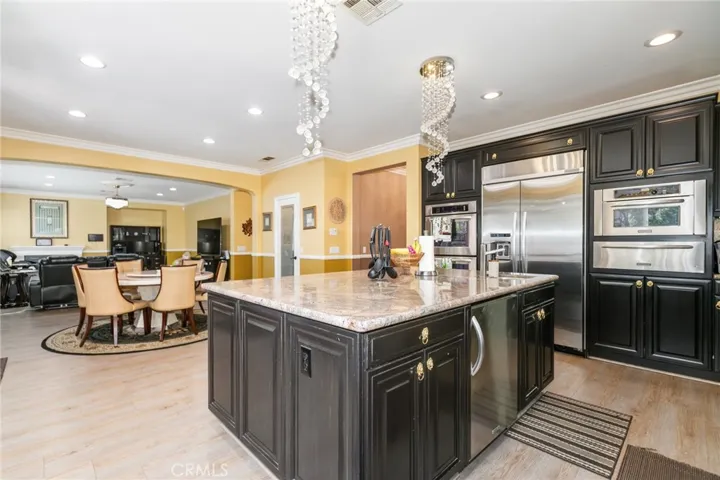 Center island with granite counter, bull nose edges, side cabinet for storage, built-in refrigerator, two center chandelier with three color lighting