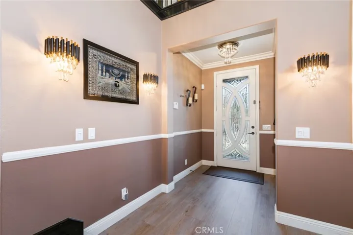 Entrance door from inside upgraded with crown molding, chandelier and beautiful light fixtures