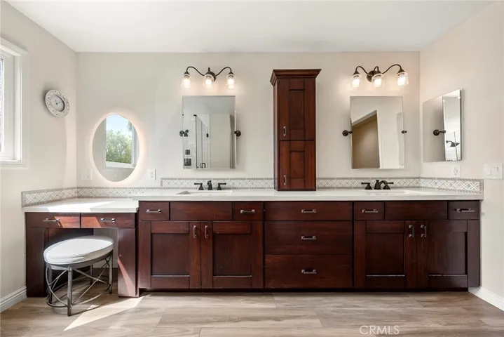 Another view of the remodeled primary bath shows new everything: lighting, counters, cabinetry and wood-looking plank ceramic tile flooring.