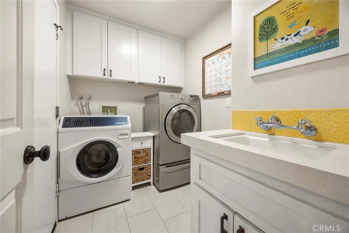 Inside laundry room has been updated with new everything: new cabinets, new sink, new oversized ceramic tile floors.