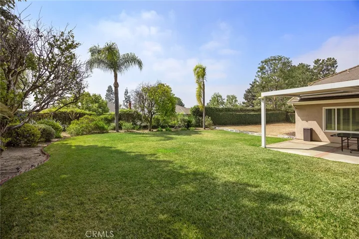 This view of the backyard shows the grassy spaces, the horse area, and the covered patio.