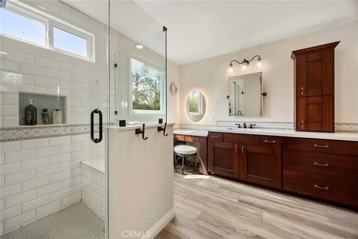 Primary bath is luxuriously appointed with spacious shower and bench seating; dual vanity sinks, and makeup table with exquisite lighting (both natural and incandescent lighting).