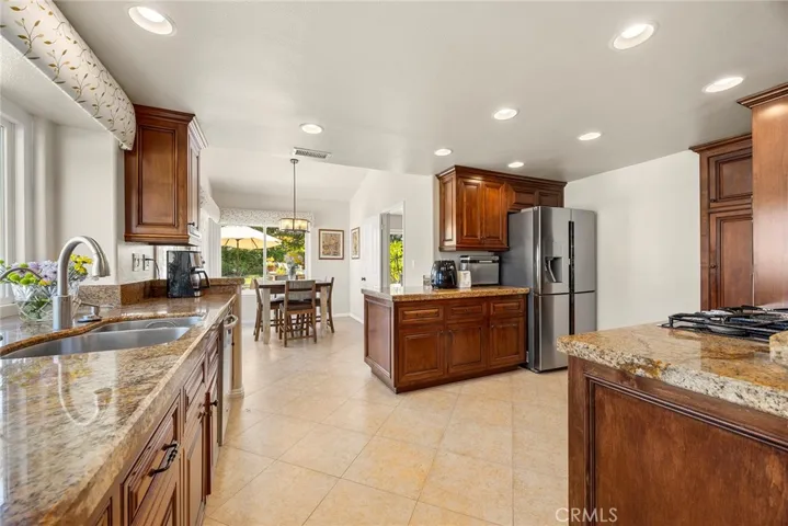 Because the kitchen is the heart of the home, it is centrally located between the breakfast nook and family room. Note the stainless steel sink on the left. Large window over the sink brings in light as well as outdoor views.