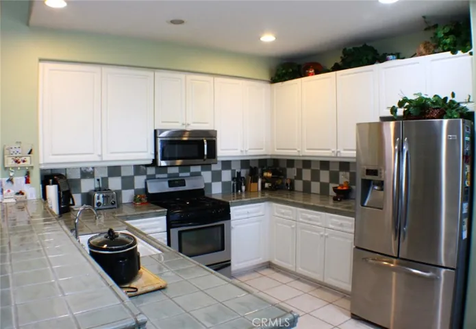 Practical Kitchen Footprint with Stainless Appliances and Custom Counters and Backsplash.