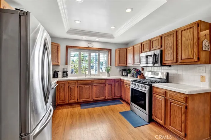 Extra Large Upgraded Kitchen Features Tile Countertops, Natural Wood Cabinetry, Tray Ceiling w/LED Lighting, Triple Sink with Kohler Faucet, and Stainless Appliances, Including 5-Burner Gas Samsung Range, Microwave, & KitchenAid Dishwasher.
