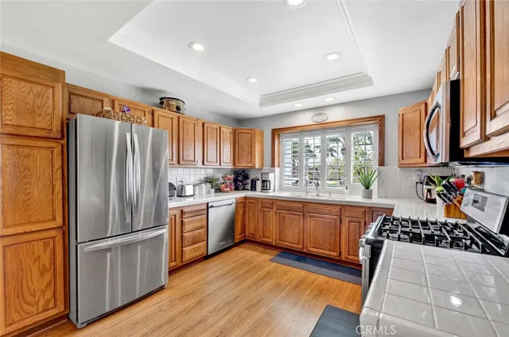 Extra Large Upgraded Kitchen Features Tile Countertops, Natural Wood Cabinetry, Tray Ceiling w/LED Lighting, Triple Sink with Kohler Faucet, and Stainless Appliances, Including 5-Burner Gas Samsung Range, Microwave, & KitchenAid Dishwasher.