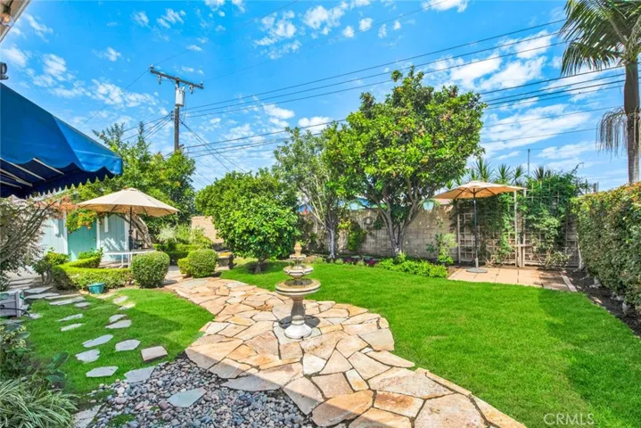 Large Private Backyard is Truly a Tranquil Sanctuary from the Outside World with its Lush Foliage, Fountain, Covered Patio, Awning, Flagstones, Lawn, Brick-Accented Decking, Vegetable Garden Area, Custom-Built Shed that Matches the House, 2 Additional Secluded Patio Areas, and Multiple Fruit Trees - Avocado, Pomegranate, 2 Orange, Lemon, Limon, Grapefruit, and Apple.