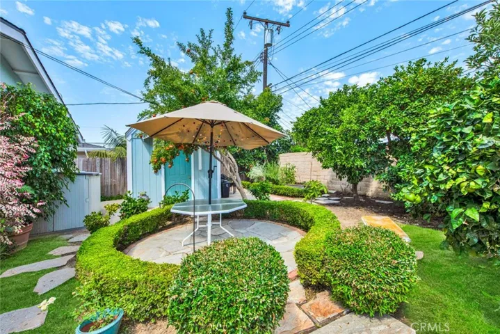 Large Private Backyard is Truly a Tranquil Sanctuary from the Outside World with its Lush Foliage, Fountain, Covered Patio, Awning, Flagstones, Lawn, Brick-Accented Decking, Vegetable Garden Area, Custom-Built Shed that Matches the House, 2 Additional Secluded Patio Areas, and Multiple Fruit Trees - Avocado, Pomegranate, 2 Orange, Lemon, Limon, Grapefruit, and Apple.