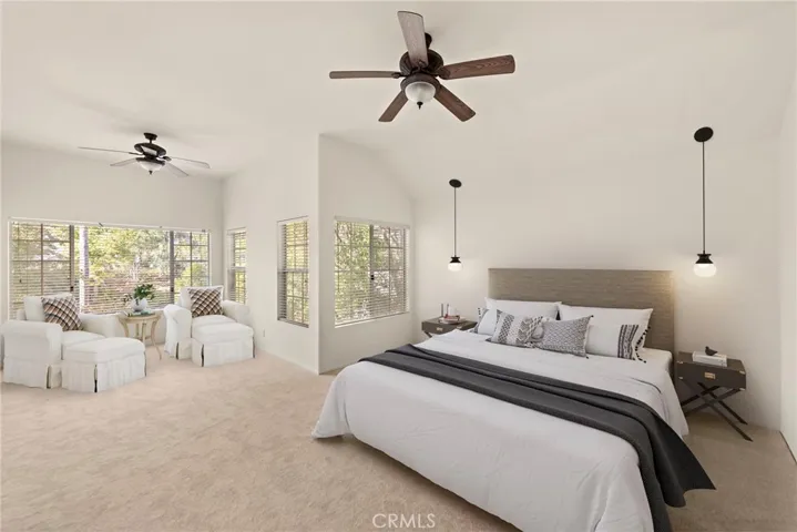 Spacious en suite main bedroom with vaulted ceiling, ceiling fans, retreat area, spa-like bath and custom wood built-ins in both closets (virtual staging)