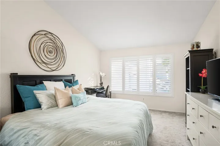 The primary bedroom has vaulted ceilings and a large window, creating a welcoming environment!