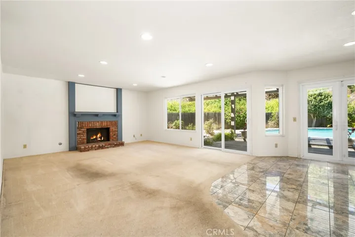 Spacious Firelit Family Room Enjoys Views of the Backyard and Pool Area
