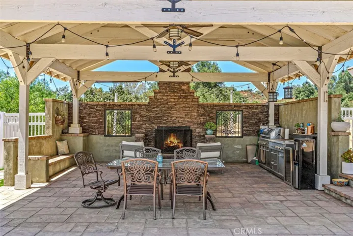 Outdoor Sitting Area Complete With Ceiling Fans & A Stacked Stone Fireplace