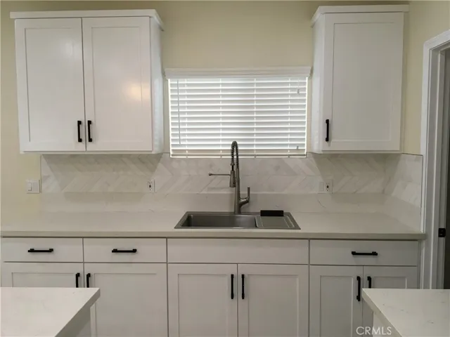 A view of the sink and kitchen cabinets.