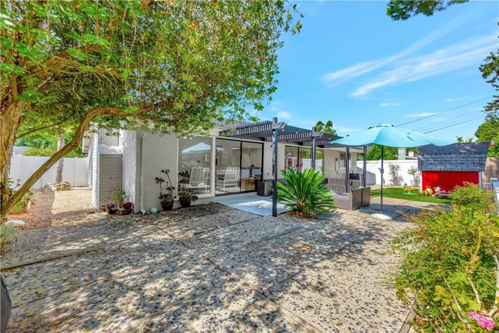 Private backyard features mature trees and covered pergola area.