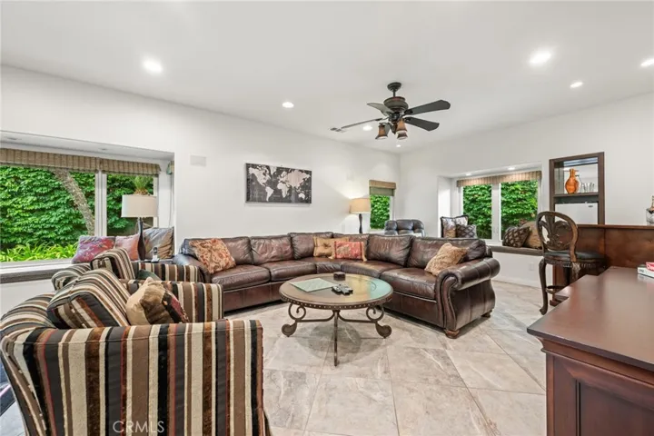 This is the other side of the 2nd family room, located at the rear of the home with built-in window seats, a bar area, lots of windows for natural light, stone floors and a pool table is just out of sight.
