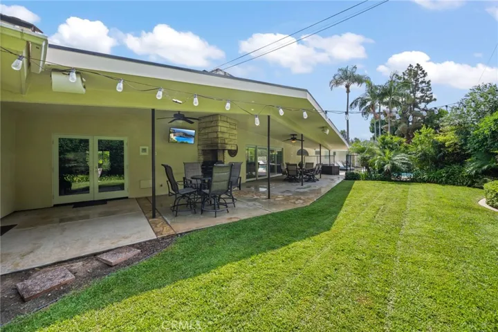 A view of the outdoor covered dining space and a portion of the grassy yard.