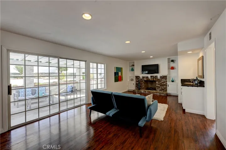 Rich colored flooring, brick gas starter fireplace with hearth and mantle, a wet bar, recessed lighting along with lots of natural light fill this family room.