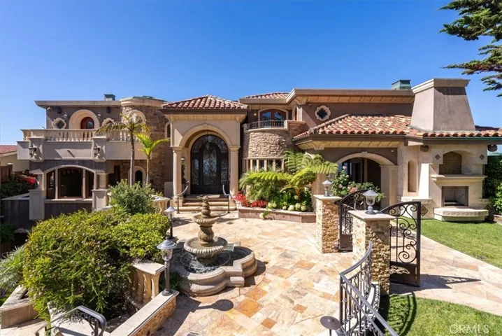 Travertine courtyard, surrounded by lush landscaping, roses, and water features