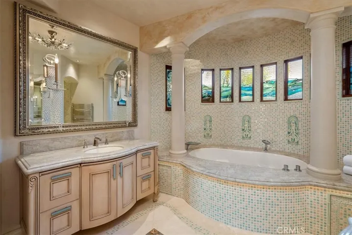 Primary en suite with walk-in shower, heated bench, crystal-accented vanities & a soaking tub