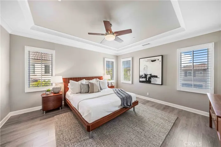 Master suite with coffered ceiling, ceiling fan, hardwood flooring and nature lighting