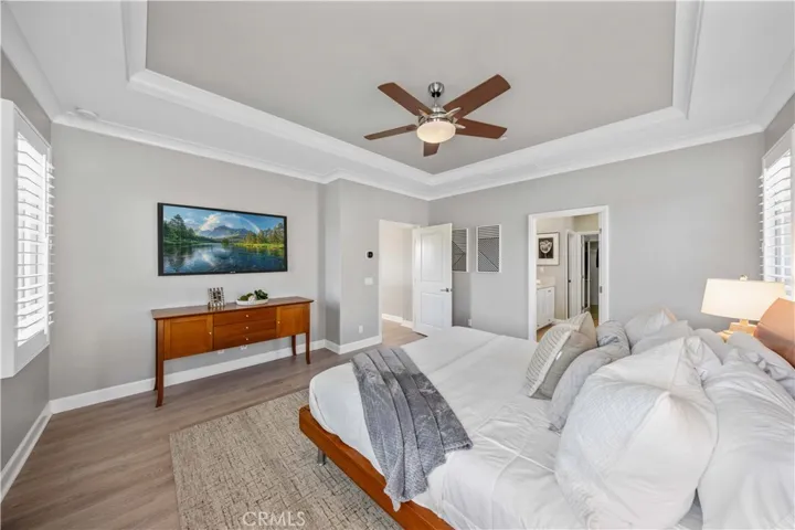 Master suite with coffered ceiling, ceiling fan, hardwood flooring and nature lighting