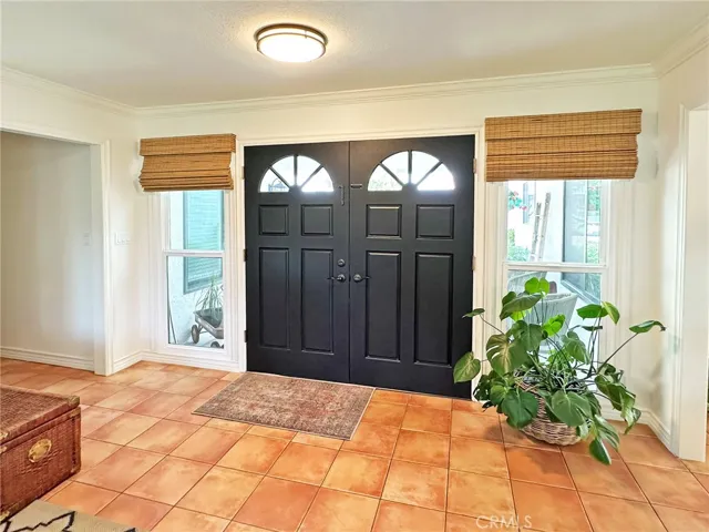 Custom front blinds frame dual pane side windows and double door entry.  Crown moulding and scraped ceilings accentuate the light and bright openness of this space.