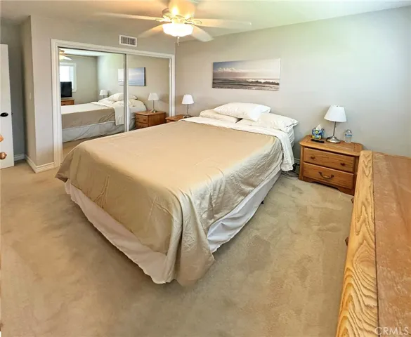Second bedroom has large closet with mirrored doors, dual pane windows, paneled door, and ceiling fan.