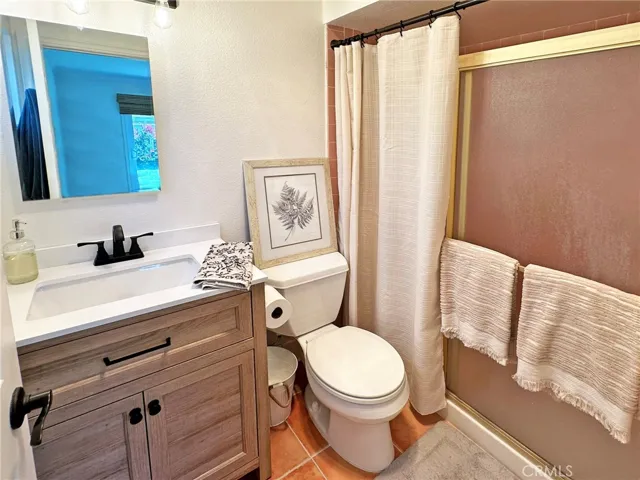 The pristine primary on-suite bath has new vanity, new lighting, and tiled shower.