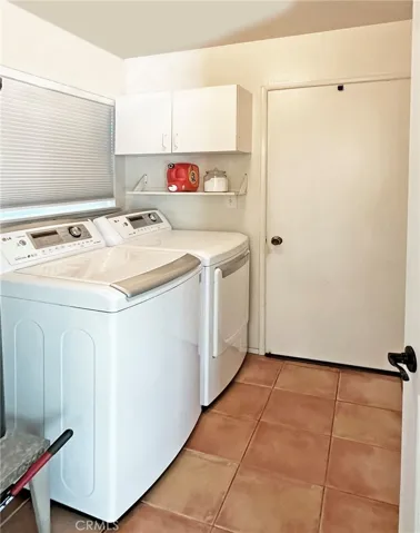  Indoor laundry room has cabinets for extra storage.