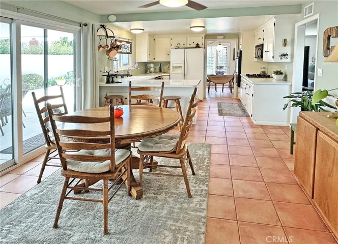Large dining area off kitchen with ceiling fan has dual pane sliding door with custom casements that opens to covered patio side yard.  Kitchen also has breakfast bar for additional seating and wor space.