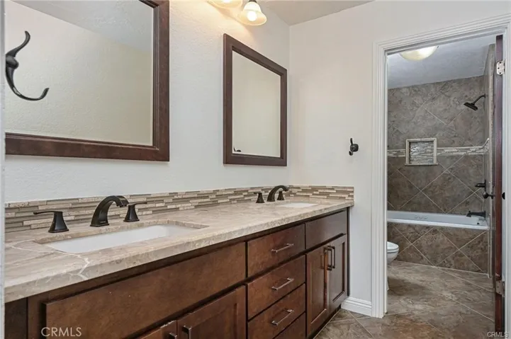 Primary Bathroom with dual sinks and separate toilet/shower area