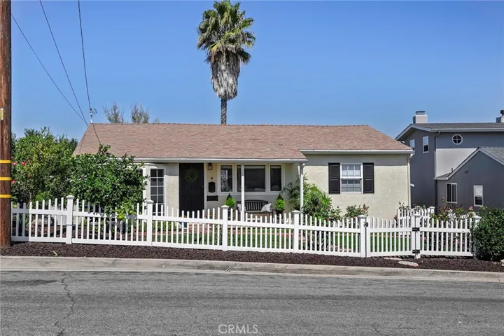 Curb appeal abounds! White picket fence encloses rosebush-filed front yard