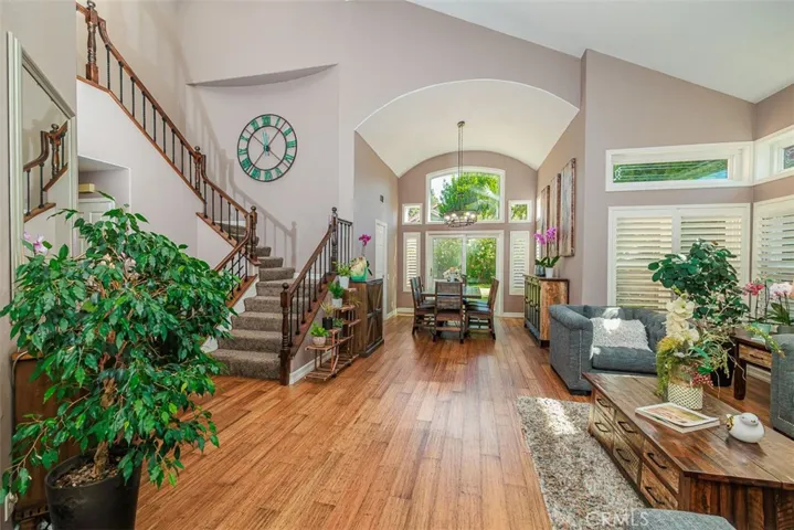 Stepping through the entrance and into the living room filled with natural light. Beautiful bamboo flooring, two-story ceilings, and rich designer tones are in abundance