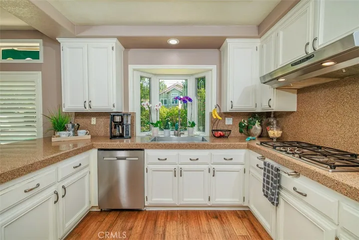 Stainless appliances, stainless farm house sink, and beveled glass greenhouse window with a view of the backyard