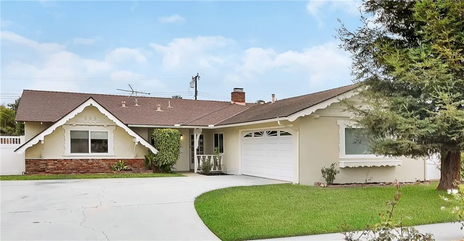 This beautifully maintained single-story home offers great curb appeal with freshly painted trim, a wide curved driveway, and lush mature landscaping that includes vibrant rose bushes