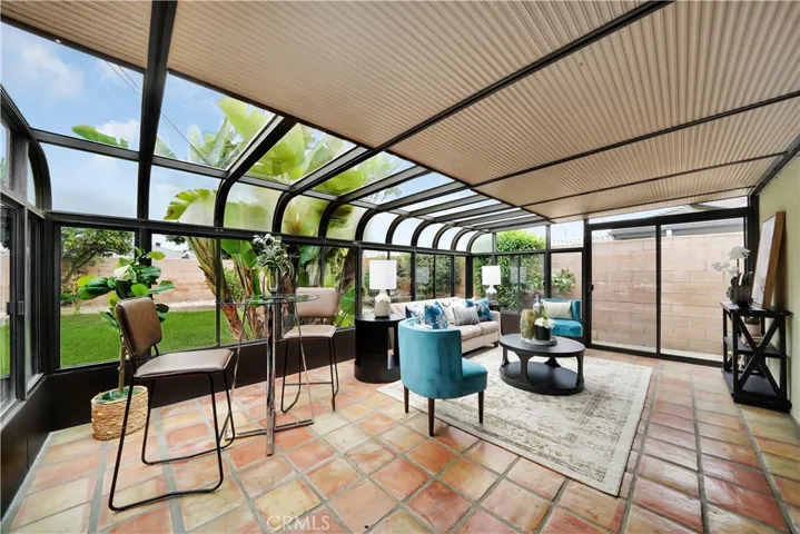 The solarium, with its terra cotta pavers and natural light, provides an ideal space for dining, relaxing, or entertaining.