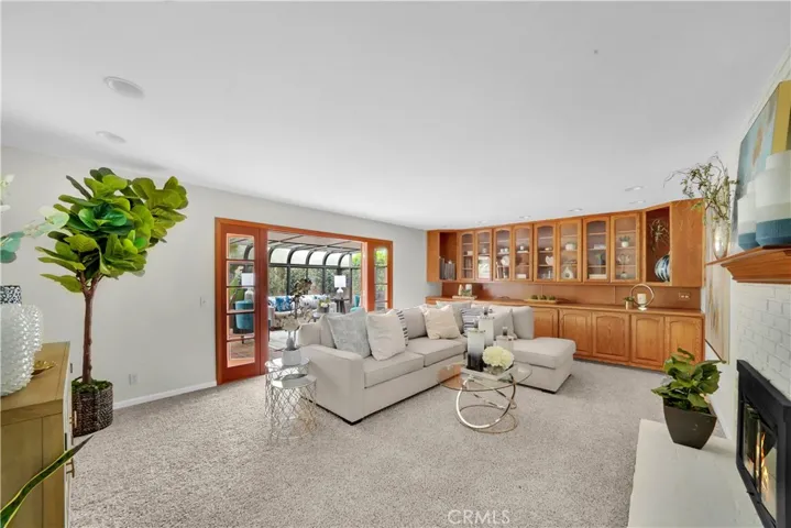 Custom built-in cabinetry with glass fronts offers plenty of storage and display space, while large French doors lead to the sun-drenched solarium.